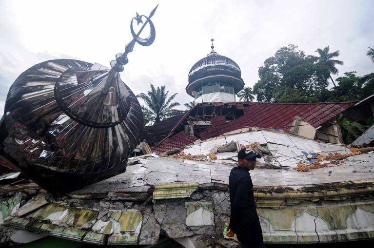 A man stands near a damaged building after an earthquake