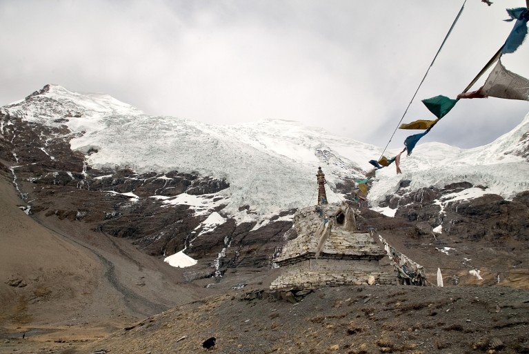 Prayer flags suspended from a shrine near a glacier on the Tibetan Plateau