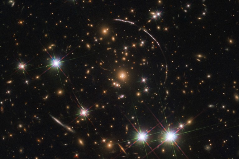 Hubble Space Telescope image of a galaxy with bright starts four bright arcs around the edges