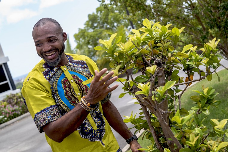 Damain Cohall stands by a native plant in Barbados.