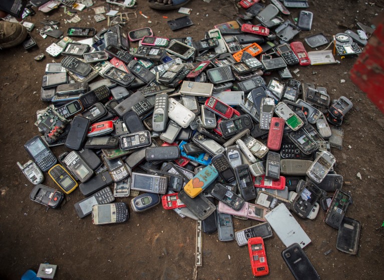A large pile of old mobile phones on the ground of an electronic scrap yard
