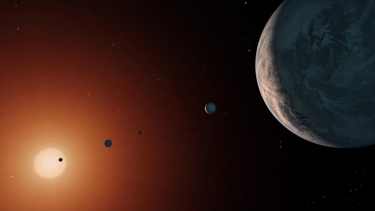 Artist's impression of the TRAPPIST-1 system from near planet TRAPPIST-1f: a number of small planets in front of a star.