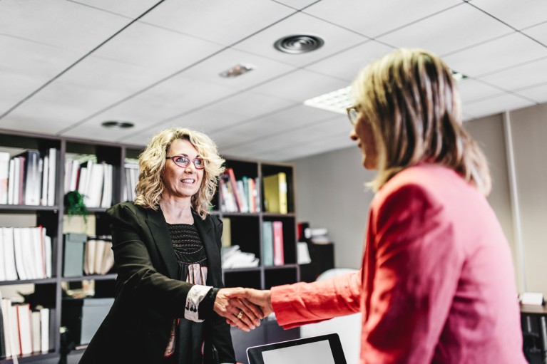 Two businesswomen shaking hands in an office.