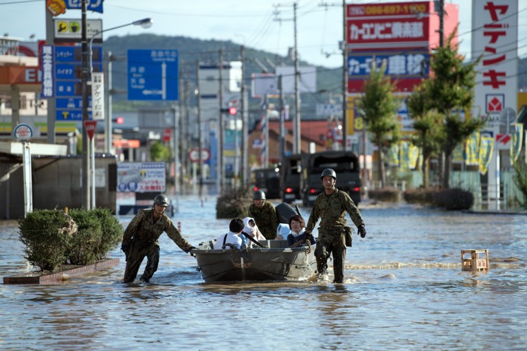Soldiers ferry people in a small boat down a street following heavy flooding in Japan.