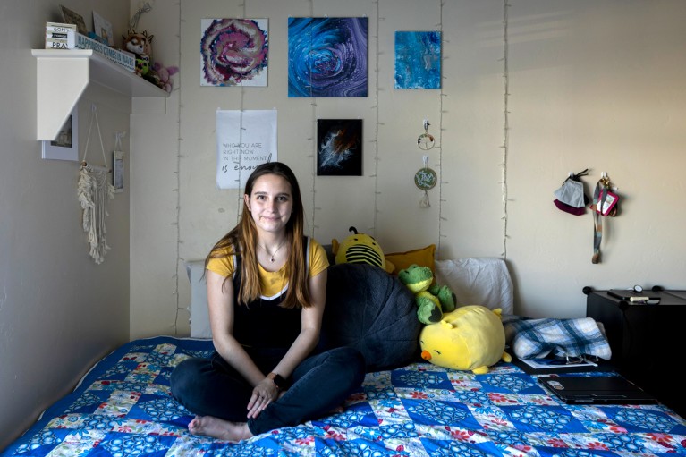 Mikayla Olsten poses for a portrait while sitting on her bed in her dorm room