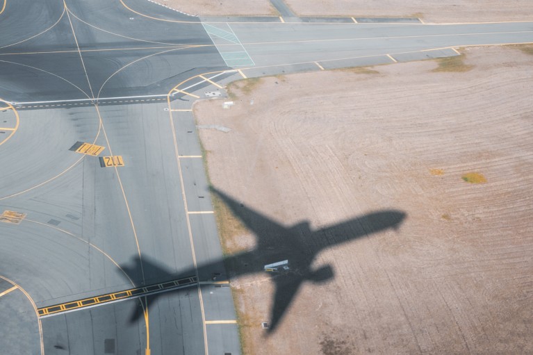 The shadow of an aeroplane is seen on the runway, taken from the plane.