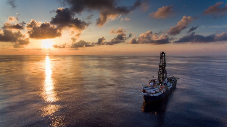 The JOIDES Resolution drillship pictured at sea during sunset.