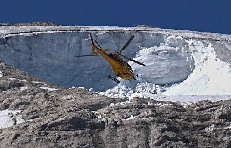 A rescue helicopter flies over the Punta Rocca glacier that collapsed near Canazei, on the mountain of Marmolada, Italy.