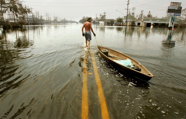 一名男子拉着独木舟沿着受灾严重的新奥尔良圣伯纳德查尔梅特社区被水淹没的街道前进。