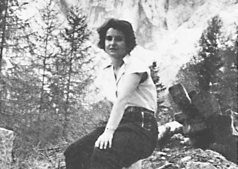 Black and white image of Rosalind Franklin resting on a post while out hiking in Norway