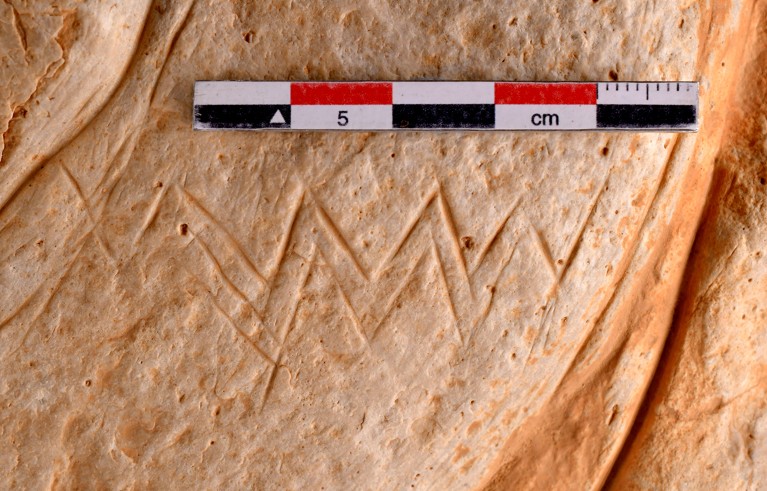 Photograph of a stone engraved with zig-zag lines.