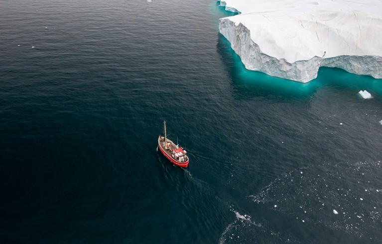 A typical Greenlandic fishing boat in front of the huge icebergs of the (Ilullisat) Icefjord, Disko Bay, western Greenland.