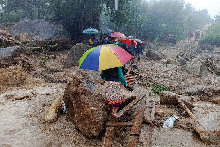 人拿着大伞走过一个临时木桥在暴雨洪水