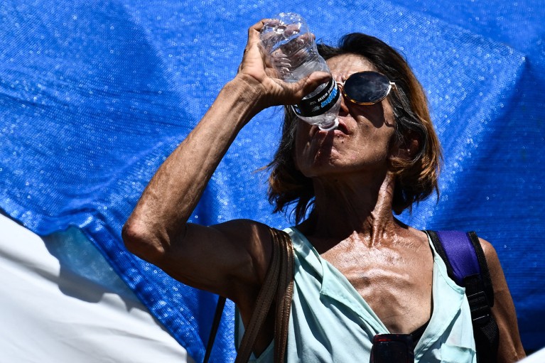 A person drinks a bottle of water in a vast homeless encampment in Phoenix, Arizona during a record heat wave.