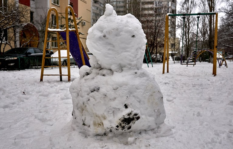A dirty snowman at a playground during a snowy winter.
