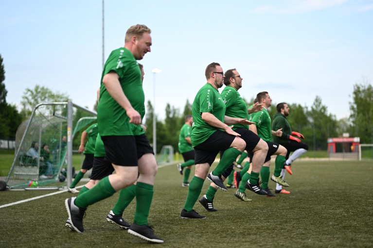 Members of a football team wearing a green kit warm up before their match