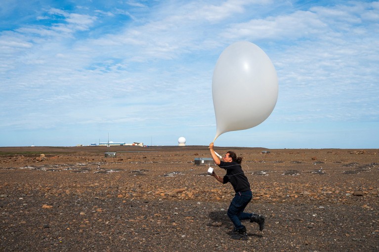 Axel Bres releases a weather balloon in the air on Kerguelen Island.