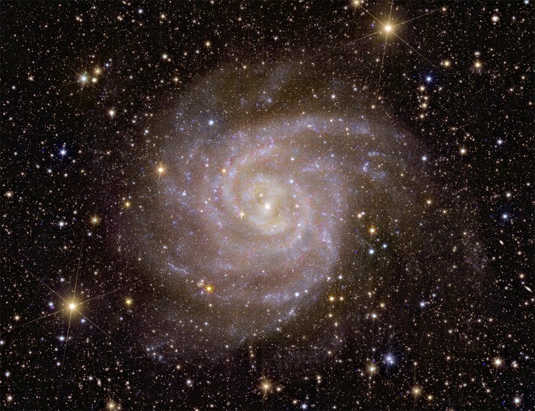 Spirals of pink and yellow stars against a detailed star field.