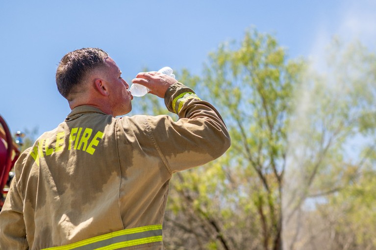 A firefighter takes a water break while combatting a wildfire during an excessive heat warning in Texas.
