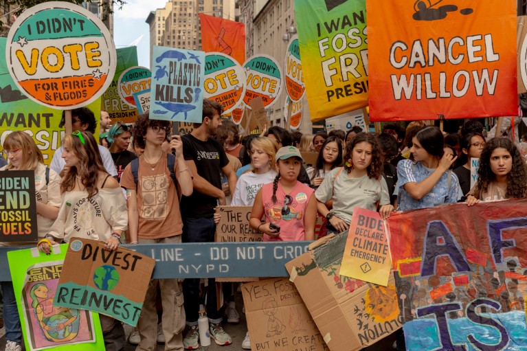 Climate protesters holding colourful signs march through New York