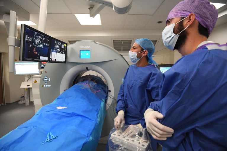 A radiologist and an assistant wearing face masks check a screen during cryotherapy treatment on a patient with kidney cancer