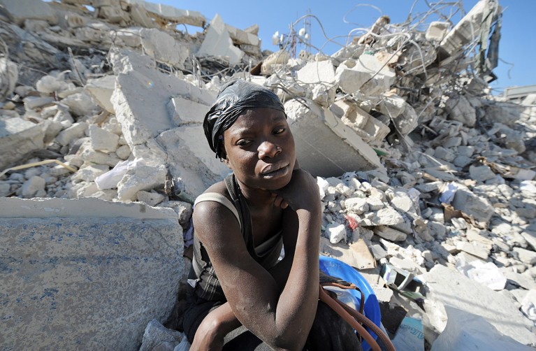 A Haitian woman rests siting on the rubbles of a destroyed building at a market in Port-au-Prince on January 22, 2010 following the massive 7.0-magnitude quake.