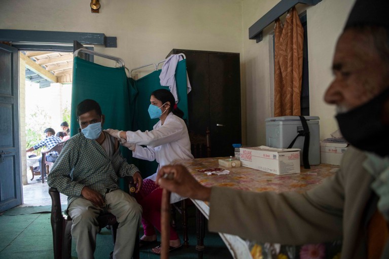 A nurse administers a dose of COVID-19 vaccine to a man in India
