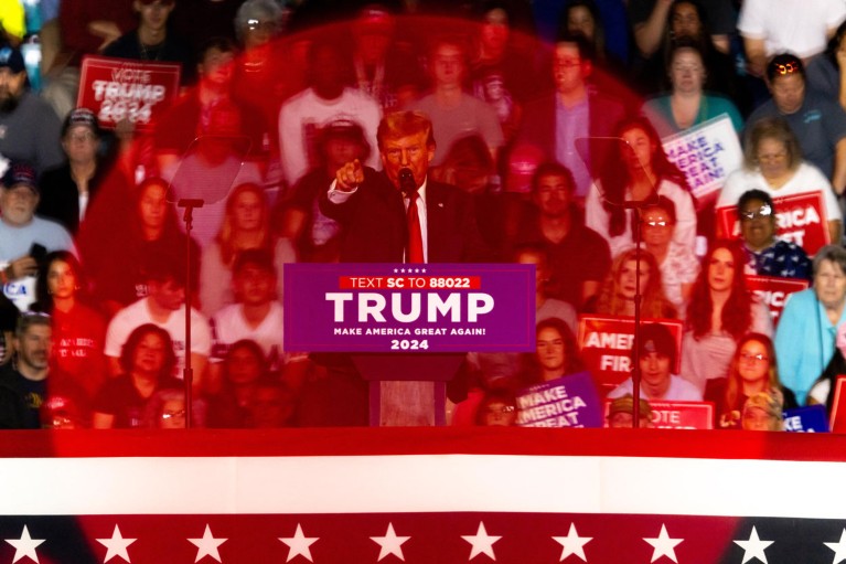 Donald Trump, seen through a circle of red light, speaks to crowds of supporters at a 2024 presidential election rally
