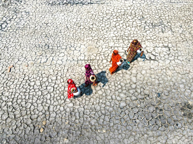 Aerial view of four women walking across a drought-struck lake