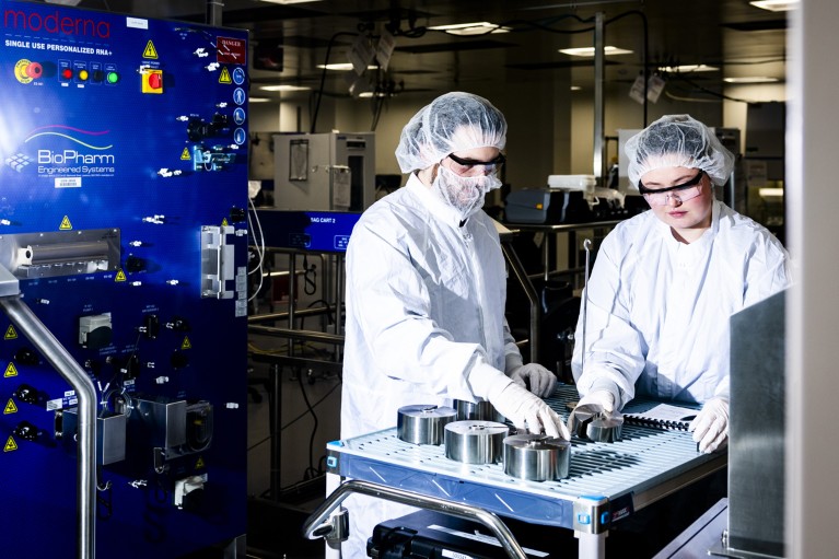 身穿白大褂、戴着发网的Moderna员工在专注于癌症疫苗研究的实验室里，在一台机器上工作