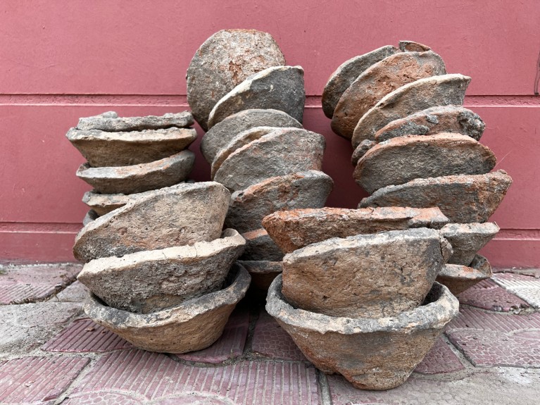 A close-up of ancient bowls stacked against a red wall