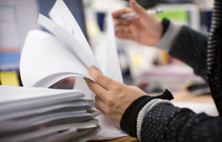 Hand flicking through a stack of papers.