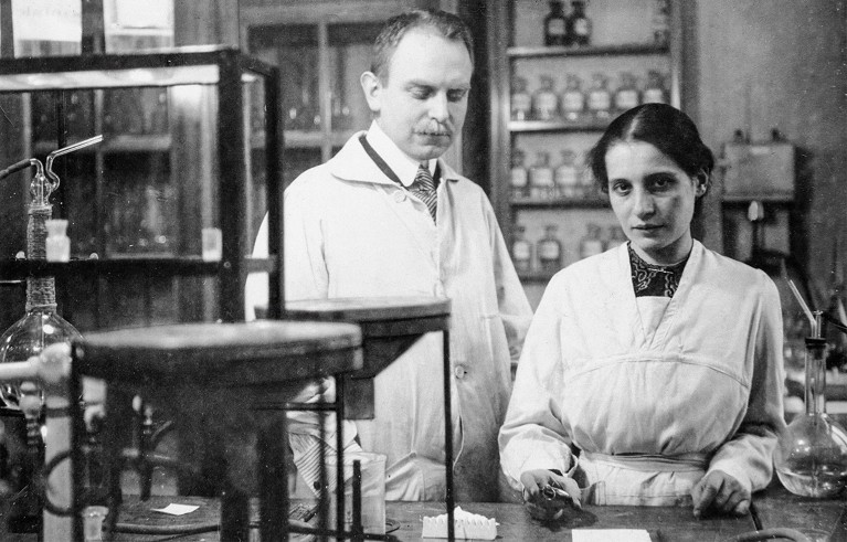 Otto Hahn and Lise Meitner standing behind a bench in ther lab