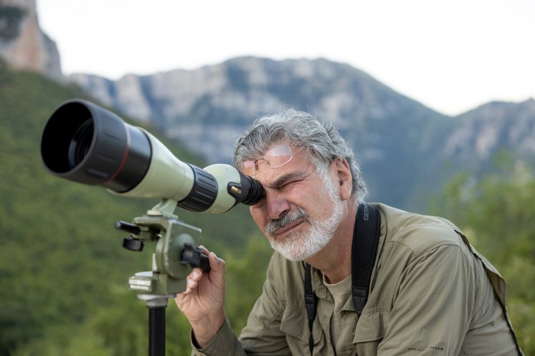 Haritakis Papaioannou looking through a telescope in a mountainous landscape.