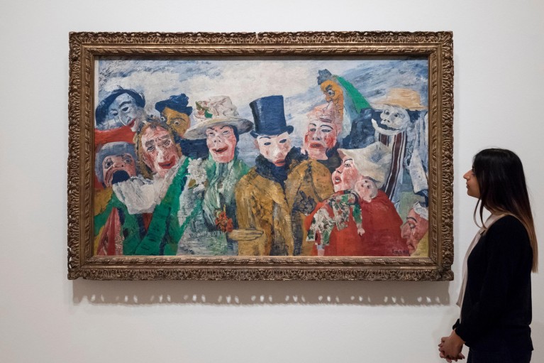 A staff member stands on the right hand side of the frame and looks at the painting titled "The Intrigue, 1890"