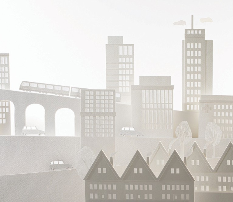 Paper cut-out cityscape featuring layered buildings, a train on a bridge, cars, and trees, against a light background.