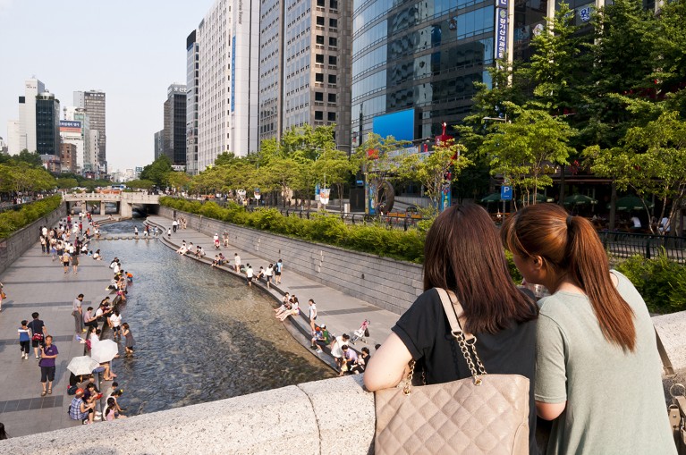 People stand on a bridge and watch others enjoy the water in the Cheonggyecheon River Restoration project in Seoul, South Korea.