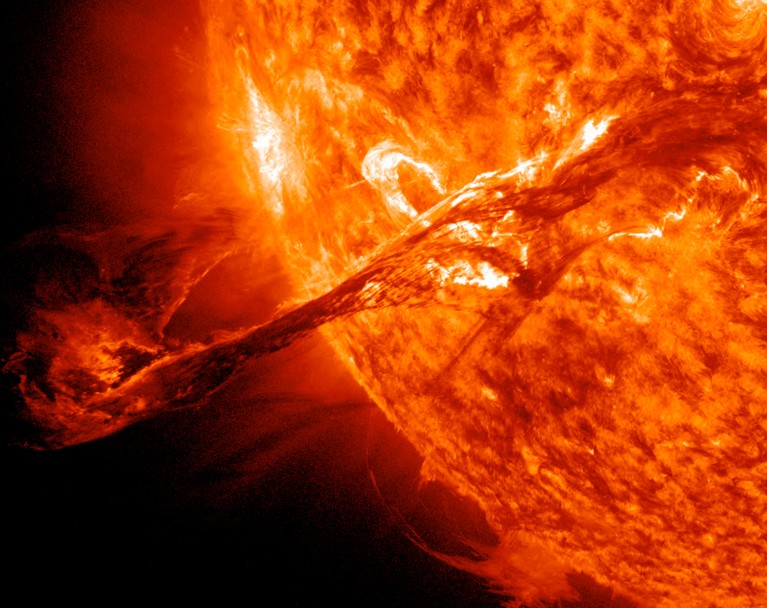 Close-up ultraviolet image of the Sun showing a powerful solar flare and a coronal mass ejection arcing outward from the solar surface