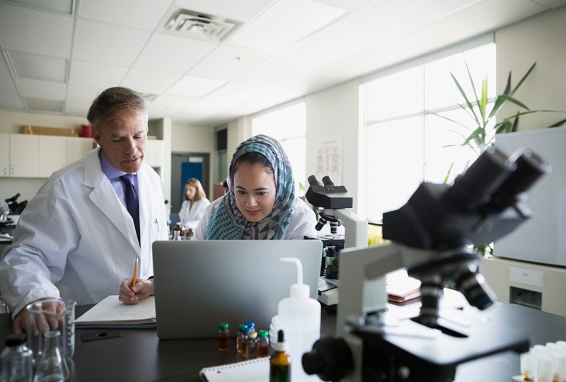 Professor and college student at laptop in science laboratory