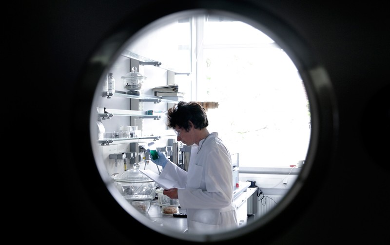 Female chemist working in lab watched through spy hole