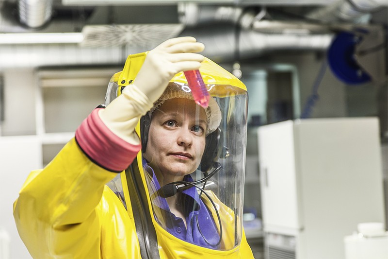 A worker in protective gear examines a vial at a BSL-4 lab in Germany.