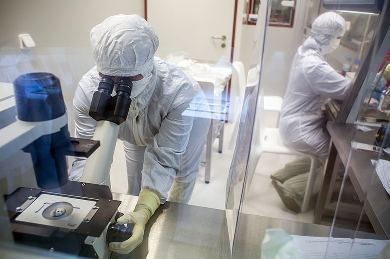 A laboratory specialist uses a microscope to check cells in a clean laboratory.