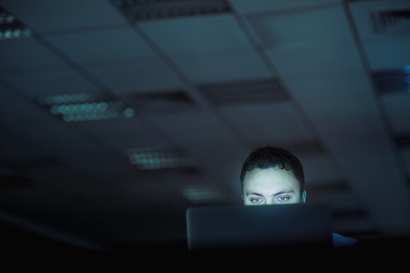 Man looking at laptop computer in office at night