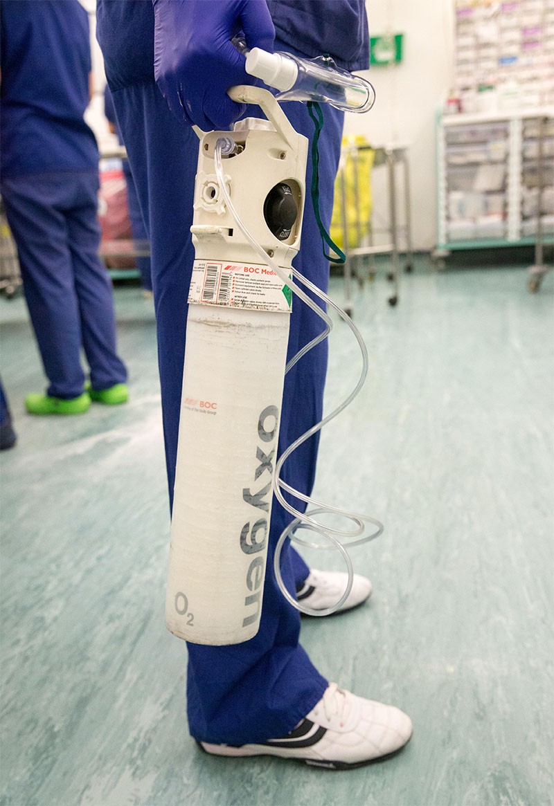 A Theatre technician holds an oxygen cylinder in preparation for an operation