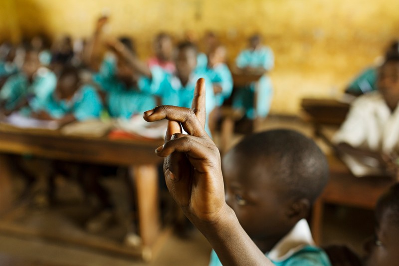 Pupils at a school in Uganda hold up their hands in class